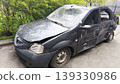 A damaged car with visible dents and impact marks is parked in a courtyard, symbolizing the consequences of an accident, vehicle damage and the concept of road safety.  139330986