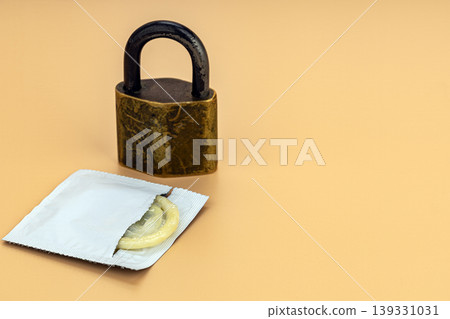 Open condom packet partially unwrapped beside an aged brass padlock on a warm beige background, representing safe sex, sexual health, and contraception protection concept Open condom packet partially unwrapped beside an aged brass padlock on a warm beige background, representing safe sex, sexual health, and contraception protection concept 139331031