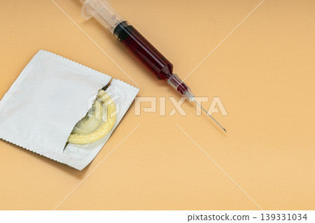 Open Condom Packet with Yellow Condom Beside a Blood-Filled Medical Syringe on Beige Background Representing Sexual Health, HIV Risk, and STI Prevention Concepts Open Condom Packet with Yellow Condom Beside a Blood-Filled Medical Syringe on Beige Background Representing Sexual Health, HIV Risk, and STI Prevention Concepts 139331034