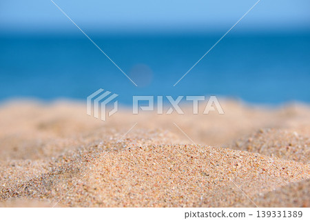Close up of clean yellow sand surface covering seaside beach with blue sea water on background. Travel and vacations concept. Close up of clean yellow sand surface covering seaside beach with blue sea water on background. Travel and vacations concept. 139331389