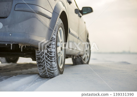 Close up of a car tire parked on snowy road on winter day. Transportation and safety concept. 139331390