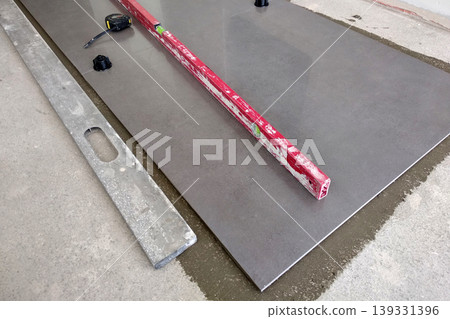 Ceramic tiles and tools for tiler. Floor tiles installation. Home improvement, renovation - ceramic tile floor adhesive, mortar, level 139331396