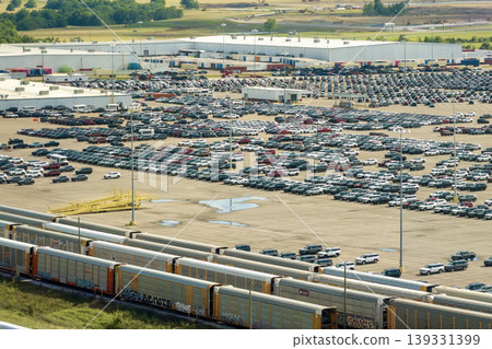 Cargo train transporting cars. Factory parking lot with many brand new cars for sale. Development of American automotive industry concept Cargo train transporting cars. Factory parking lot with many brand new cars for sale. Development of American automotive industry concept 139331399