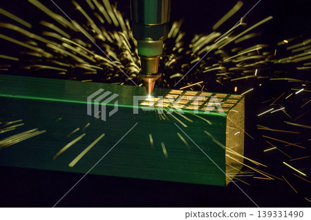 Close-up of a fiber laser cutting machine engraving and cutting a metal square tube with intense sparks. 139331490
