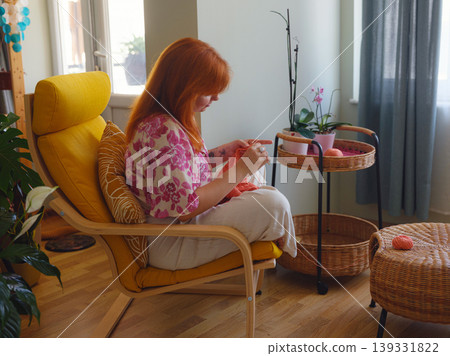 Young Woman knitting scarf in living room. doing crochet knits. 139331822