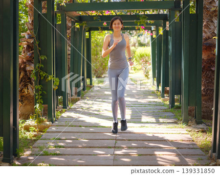 idea of healthy lifestyle and sports in a modern city. Female jogger. Fit young Asian woman running in park and enjoying healthy outdoor. Fitness girl in public park. idea of healthy lifestyle and sports in a modern city. Female jogger. Fit young Asian woman running in park and enjoying healthy outdoor. Fitness girl in public park. 139331850