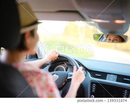 Young woman drives through scenic countryside, hands on wheel, focused on road ahead. Peaceful summer journey through rural landscapes captures freedom and adventure. Croatia, Europe Young woman drives through scenic countryside, hands on wheel, focused on road ahead. Peaceful summer journey through rural landscapes captures freedom and adventure. Croatia, Europe 139331874