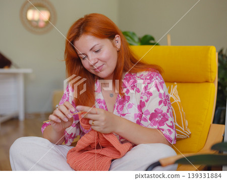 Young Woman knitting scarf in living room. doing crochet knits. Young Woman knitting scarf in living room. doing crochet knits. 139331884