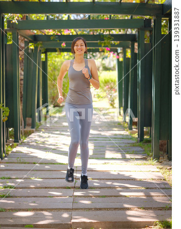 idea of healthy lifestyle and sports in a modern city. Female jogger. Fit young Asian woman running in park and enjoying healthy outdoor. Fitness girl in public park. idea of healthy lifestyle and sports in a modern city. Female jogger. Fit young Asian woman running in park and enjoying healthy outdoor. Fitness girl in public park. 139331887