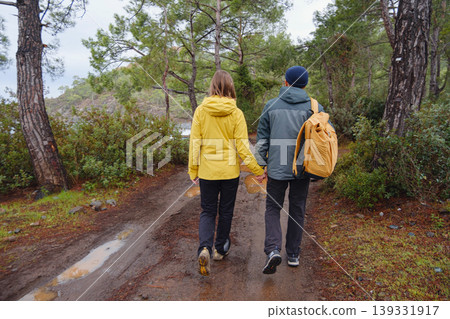 Couple enjoys Turkish coastline near Kemer. in pine forest. Sitting on stones, watching sea waves, relaxing together, slow romantic moment near calm blue water under soft winter light. Couple enjoys Turkish coastline near Kemer. in pine forest. Sitting on stones, watching sea waves, relaxing together, slow romantic moment near calm blue water under soft winter light. 139331917