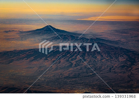 Aerial view of mountain landscape at sunset from airplane window Aerial view of mountain landscape at sunset from airplane window 139331968