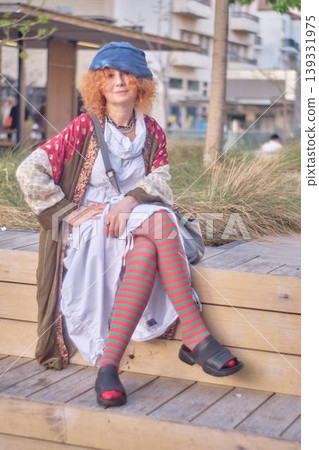 Fashionable redhead woman using smartphone outdoors, stylish young female sitting in urban environment Fashionable redhead woman using smartphone outdoors, stylish young female sitting in urban environment 139331975