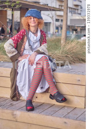 Fashionable redhead woman using smartphone outdoors, stylish young female sitting in urban environment Fashionable redhead woman using smartphone outdoors, stylish young female sitting in urban environment 139331978