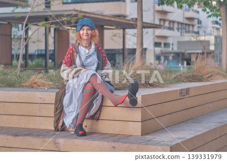 Fashionable redhead woman using smartphone outdoors, stylish young female sitting in urban environment Fashionable redhead woman using smartphone outdoors, stylish young female sitting in urban environment 139331979