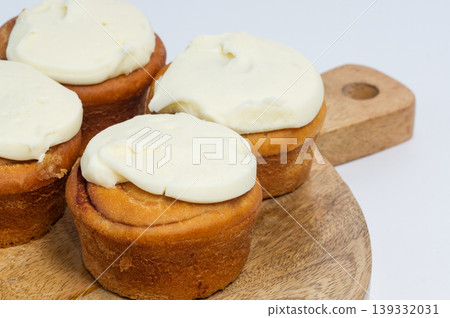 Three Cinnabon buns on a wooden Board with a napkin on a light background. American classic bun 139332031
