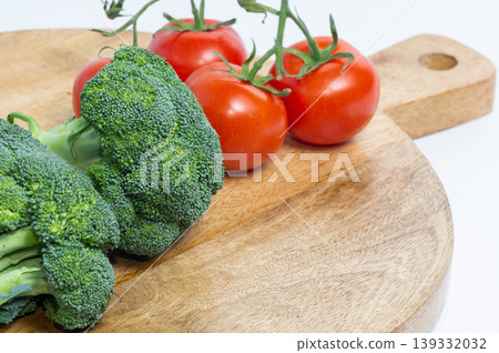 Tomatoes on the vine and broccoli lie on a wooden board. Tomatoes on the vine and broccoli lie on a wooden board. 139332032