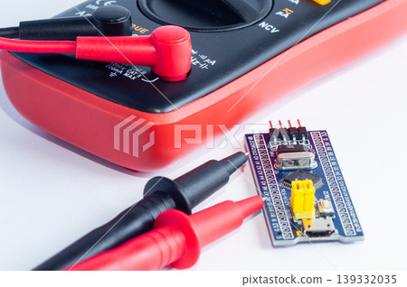 Multimeter with measurement probes and electronics board on a white background Multimeter with measurement probes and electronics board on a white background 139332035
