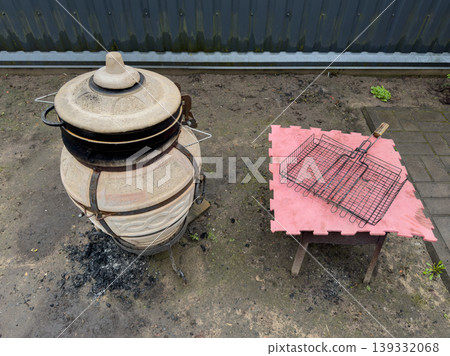 Outdoor ceramic charcoal grill with a barbecue grate for the backyard, traditional barbecue oven, and outdoor cooking equipment Outdoor ceramic charcoal grill with a barbecue grate for the backyard, traditional barbecue oven, and outdoor cooking equipment 139332068
