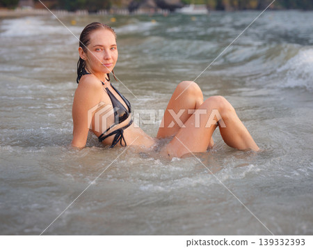 Young woman enjoying serene evening at sea in Krabi, Thailand during sunset. Calm waves, golden light, and peaceful atmosphere highlight tropical beauty and connection with nature. Young woman enjoying serene evening at sea in Krabi, Thailand during sunset. Calm waves, golden light, and peaceful atmosphere highlight tropical beauty and connection with nature. 139332393