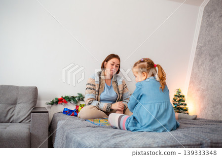 Wide shot of Caucasian mother playing board game with her little daughter. Family joyful time during the winter holidays. Copy space Wide shot of Caucasian mother playing board game with her little daughter. Family joyful time during the winter holidays. Copy space 139333348