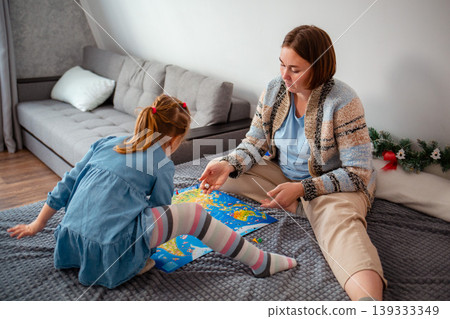 Top view of Caucasian mother and daughter play a board game together, lying on a bed in a living room. Christmas vacation 139333349