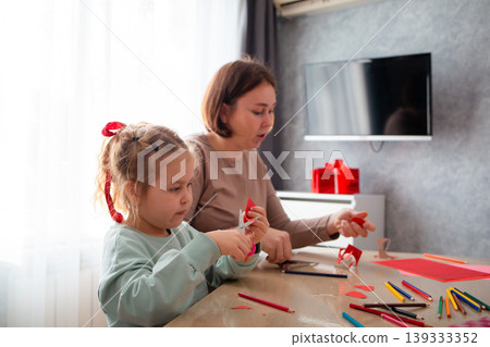 Mother and daughter is sitting at a table in the living room and making holiday crafts. The concept of Mother's Day and Valentine's Day 139333352
