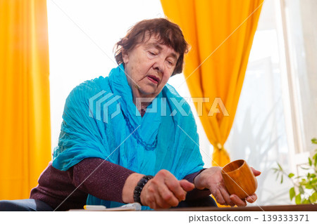Senior female using dice in a game at home. Calm mood and attention. Concept of leisure and comfort. Senior female using dice in a game at home. Calm mood and attention. Concept of leisure and comfort. 139333371