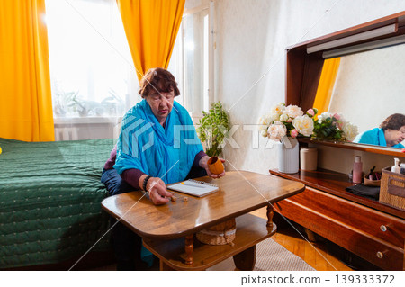 Elderly Caucasian woman rolling dice during evening time. Relaxed posture and attention. Concept of leisure and wellbeing. Wide shot Elderly Caucasian woman rolling dice during evening time. Relaxed posture and attention. Concept of leisure and wellbeing. Wide shot 139333372