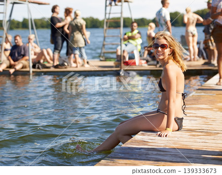 Summer, bikini and woman at lake to relax, party and people on dam, deck with water. Happy, holiday and portrait of vacation with girl in swimwear or fashion on wood, dock and sitting in sunshine Summer, bikini and woman at lake to relax, party and people on dam, deck with water. Happy, holiday and portrait of vacation with girl in swimwear or fashion on wood, dock and sitting in sunshine 139333673