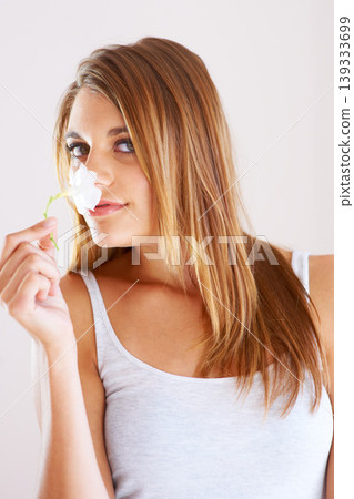 Woman, portrait and smelling a flower in studio for fragrance, scent and sustainability. Young female model person with a plant on a white background for natural beauty and fresh or sweet smell Woman, portrait and smelling a flower in studio for fragrance, scent and sustainability. Young female model person with a plant on a white background for natural beauty and fresh or sweet smell 139333699