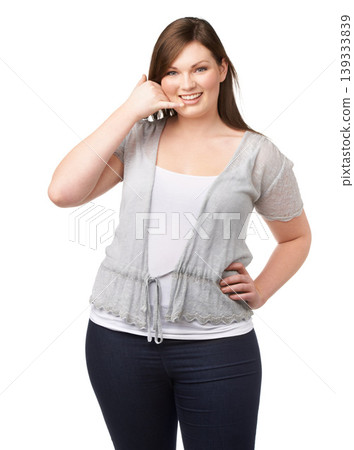 Portrait, call me hand gesture and a plus size woman in studio isolated on a white background for communication. Smile, finger phone and a happy young person feeling body positive while flirting Portrait, call me hand gesture and a plus size woman in studio isolated on a white background for communication. Smile, finger phone and a happy young person feeling body positive while flirting 139333839