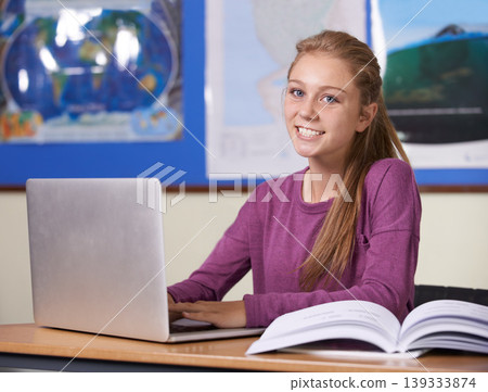 Woman, student and laptop in classroom for education, learning and research with geography or scholarship books. Portrait of young person typing on computer at high school for online map information 139333874