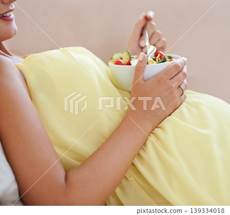 Pregnant woman, salad and bowl on sofa for health, nutrition and wellness in living room of apartment. Person, fruit and happy on couch of lounge for relax, pregnancy and healthy diet with vitamins 139334018