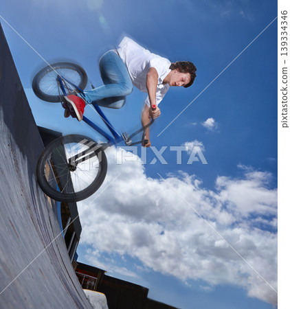Bike, ride and teenager with speed on ramp at skatepark in summer with freedom and energy on blue sky. Fast, bicycle and performance of stunt with kid in competition, contest or event for cycling Bike, ride and teenager with speed on ramp at skatepark in summer with freedom and energy on blue sky. Fast, bicycle and performance of stunt with kid in competition, contest or event for cycling 139334346
