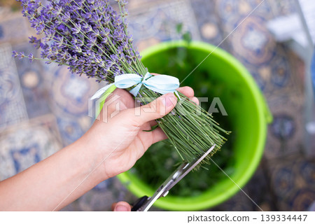 Making bouquets of lavender. Close-up shot of cut bottom part of flowers to make it even Making bouquets of lavender. Close-up shot of cut bottom part of flowers to make it even 139334447
