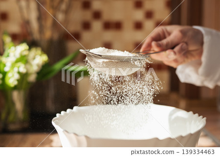 Girl sieving flour to the plate for cooking tasty and airy bread. Wife using sieve for flour in cooking 139334463