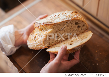 Girl checking quality of self made palianytsia bread. Fresh baked bread in hands of a hostess in the kitchen 139334476