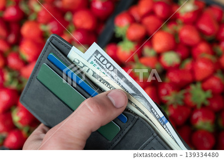 Looking through money in wallet with strawberry background at the market. Concept of buying expensive but tasty strawberry 139334480