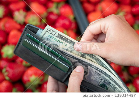 Girl taking 20 dollar bill from the wallet to buy some strawberries. Price for strawberries at the market, buying tasty berries Girl taking 20 dollar bill from the wallet to buy some strawberries. Price for strawberries at the market, buying tasty berries 139334487
