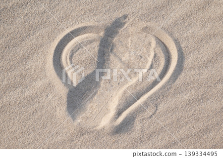Shape of heart drawn on the sand, shoe print on it, close up. Concept of lost love, broken heart, bad emotions Shape of heart drawn on the sand, shoe print on it, close up. Concept of lost love, broken heart, bad emotions 139334495