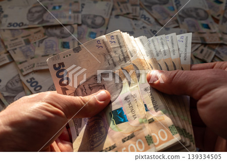 Ukrainian banknotes of 500 hryvnia nominals in male hands, close up. Money in Ukraine, good salary, purchases and finances concept Ukrainian banknotes of 500 hryvnia nominals in male hands, close up. Money in Ukraine, good salary, purchases and finances concept 139334505