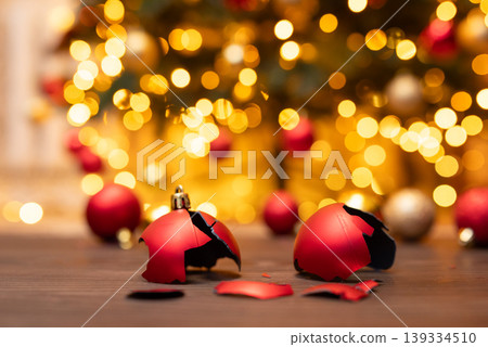 Broken christmas tree ball decoration on the floor. Broken decoration, christmas tree in brights lights on the background Broken christmas tree ball decoration on the floor. Broken decoration, christmas tree in brights lights on the background 139334510