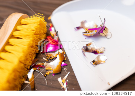 Shattered christmas tree bauble ball decoration on the floor. Cleaning floor from broken glass ball decoration with brush and scoop Shattered christmas tree bauble ball decoration on the floor. Cleaning floor from broken glass ball decoration with brush and scoop 139334517