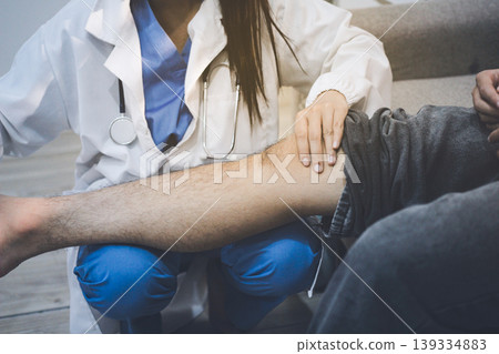 Female doctor examining male patient leg in hospital Female doctor examining male patient leg in hospital 139334883