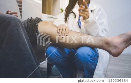 Female doctor examining male patient leg in hospital Female doctor examining male patient leg in hospital 139334884