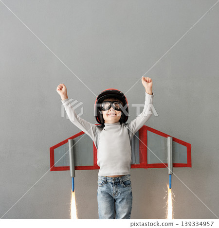 Happy child pretend to be astronaut. Funny kid with paper rocket. Little boy playing indoors Happy child pretend to be astronaut. Funny kid with paper rocket. Little boy playing indoors 139334957