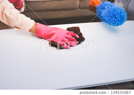 Person cleaning the room, cleaning staff is using cloth and spraying disinfectant to wipe the tables in the company office room. Cleaning staff. Maintaining cleanliness in the organization. Person cleaning the room, cleaning staff is using cloth and spraying disinfectant to wipe the tables in the company office room. Cleaning staff. Maintaining cleanliness in the organization. 139335067