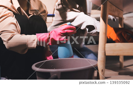 Person cleaning the room, cleaning staff is using cloth and spraying disinfectant to wipe the tables in the company office room. Cleaning staff. Maintaining cleanliness in the organization. 139335092