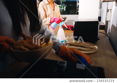 Person cleaning the room, cleaning staff is using cloth and spraying disinfectant to wipe the tables in the company office room. Cleaning staff. Maintaining cleanliness in the organization. Person cleaning the room, cleaning staff is using cloth and spraying disinfectant to wipe the tables in the company office room. Cleaning staff. Maintaining cleanliness in the organization. 139335133