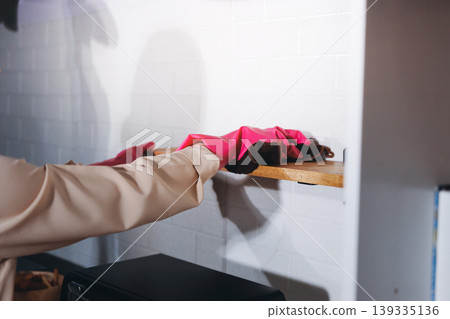 Person cleaning the room, cleaning staff is using cloth and spraying disinfectant to wipe the tables in the company office room. Cleaning staff. Maintaining cleanliness in the organization. Person cleaning the room, cleaning staff is using cloth and spraying disinfectant to wipe the tables in the company office room. Cleaning staff. Maintaining cleanliness in the organization. 139335136